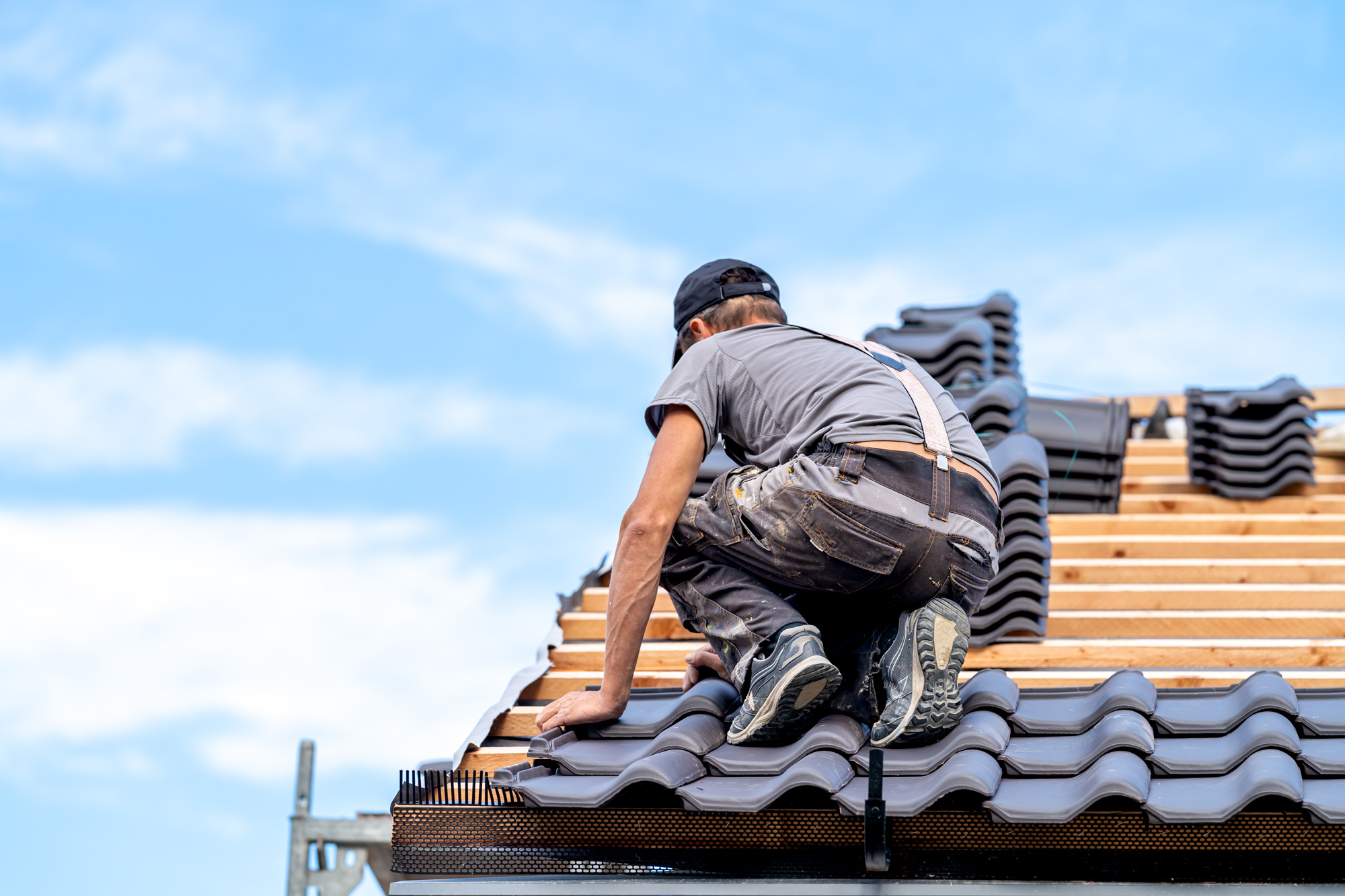 Worker laying tiles on new roof